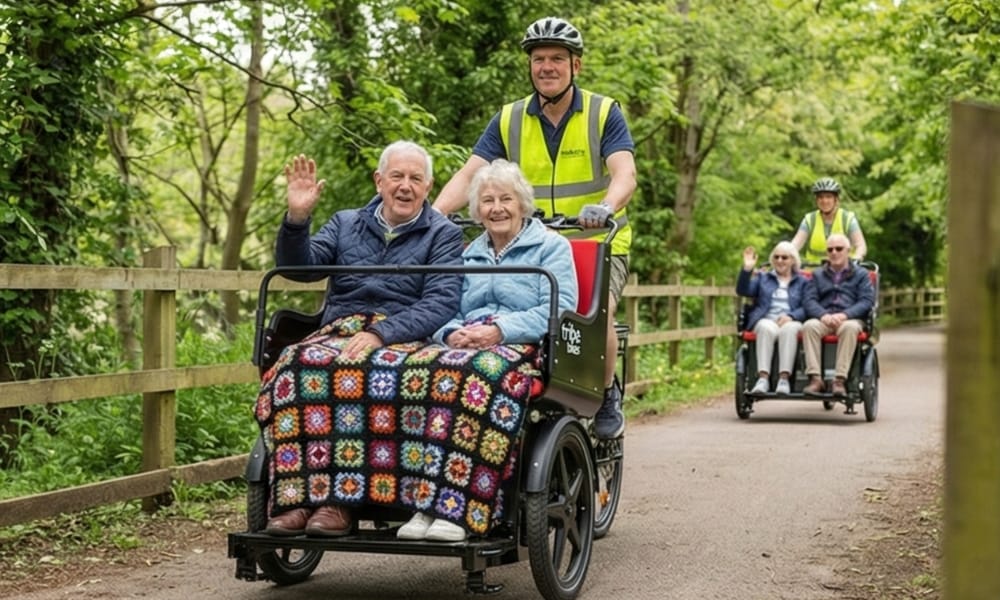 Two passengers waving from a Ricky Rickshaw on a shared path, with a second Ricky following behind